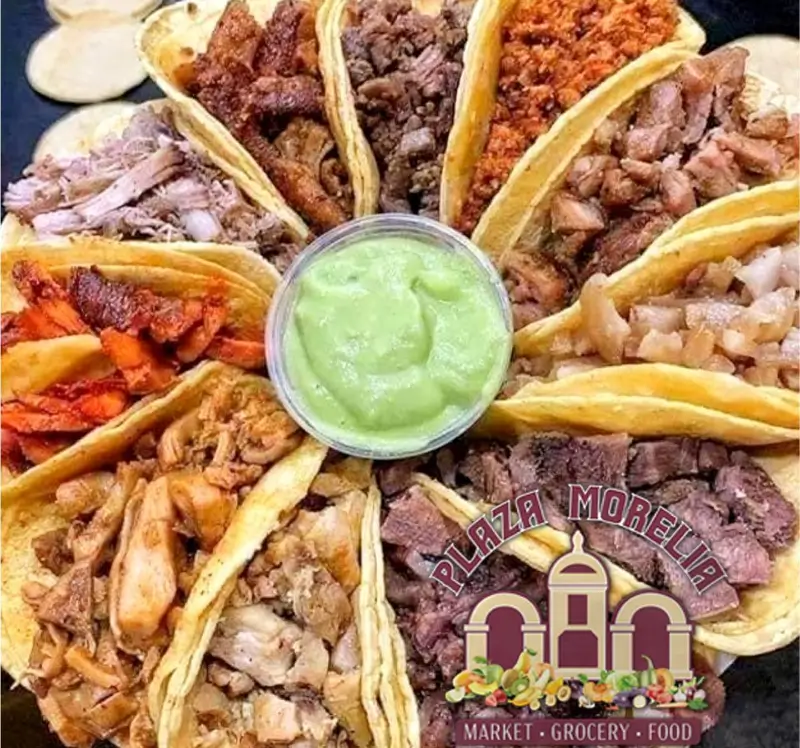 A variety of tacos surrounded by a green dipping sauce